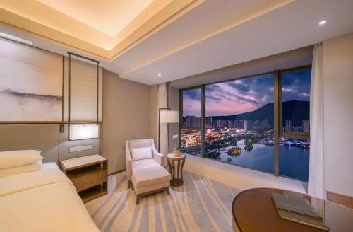 een slaapkamer met een groot raam met uitzicht op de stad bij Hilton Zhoushan in Zhoushan