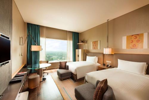 a hotel room with two beds and a television at Conrad Pune in Pune
