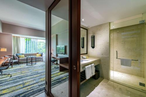 uma casa de banho com uma porta de vidro que leva a uma sala de estar em Hilton Kota Kinabalu em Kota Kinabalu