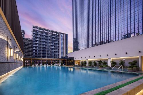 a large swimming pool in a city with tall buildings at DoubleTree by Hilton Hotel Shenzhen Longhua, Near MTR Qinghu, Shenzhen North Railway, Uniwalk & Uniworld Shopping Mall, Sam's Club, Shenzhen Art Museum New Venue, Costco in Shenzhen