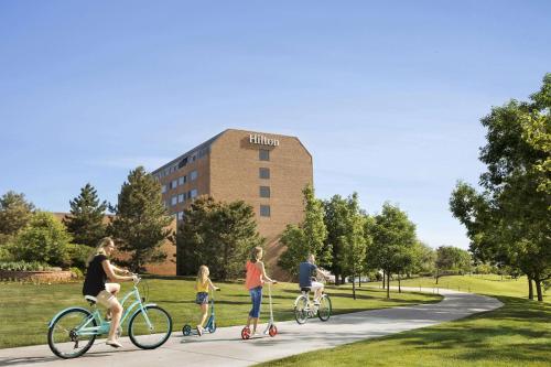 eine Gruppe von Personen, die vor einem Gebäude Fahrrad fahren in der Unterkunft The Inverness Denver, a Hilton Golf & Spa Resort in Englewood