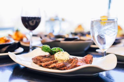 a plate of food on a table with a glass of wine at The Inverness Denver, a Hilton Golf & Spa Resort in Englewood