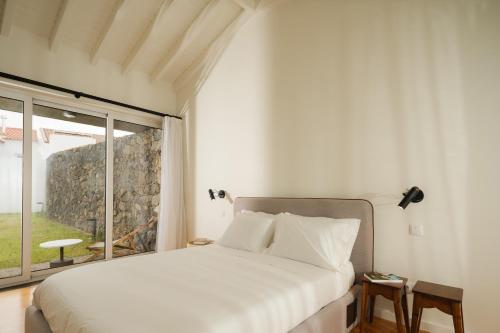 a bedroom with a bed and a large window at ENTRE MUROS - Turismo Rural - Casa com jardim e acesso direto ao mar in Ribeira Grande