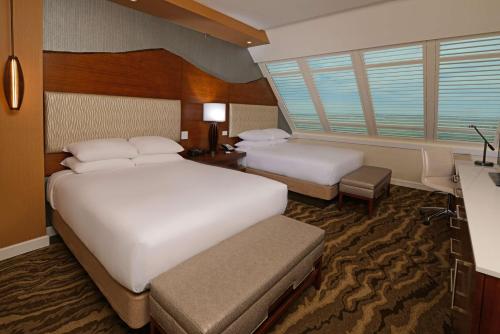 a hotel room with two beds and a desk at The Inverness Denver, a Hilton Golf & Spa Resort in Englewood