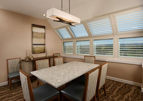 a dining room with a table and chairs and windows at The Inverness Denver, a Hilton Golf & Spa Resort in Englewood