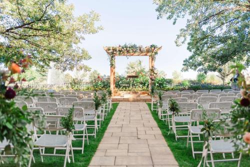 an outdoor wedding ceremony with white chairs and an altar at The Inverness Denver, a Hilton Golf & Spa Resort in Englewood