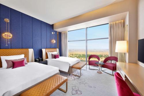 ドーハにあるAlRayyan Hotel Doha, Curio Collection by Hiltonのベッド2台と大きな窓が備わるホテルルームです。