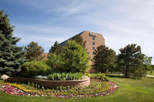 a building with a flower garden in front of it at The Inverness Denver, a Hilton Golf & Spa Resort in Englewood