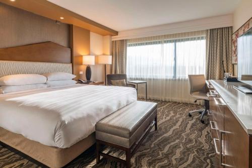 a hotel room with a large bed and a desk at The Inverness Denver, a Hilton Golf & Spa Resort in Englewood