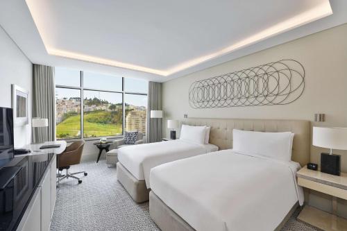 a hotel room with two beds and a television at Hilton Tanger City Center Hotel & Residences in Tangier
