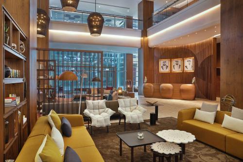 دبل تري باي هيلتون دبي - الخليج التجاري في دبي: غرفة معيشة مع أريكة صفراء وكراسي