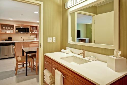 a bathroom with a sink and a mirror and a kitchen at Home2 Suites By Hilton Smyrna Nashville in Smyrna