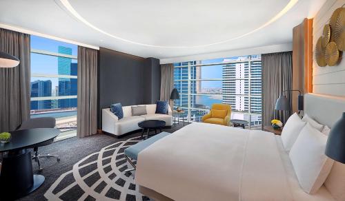 a bedroom with a large white bed and a living room at DoubleTree by Hilton Dubai - Business Bay in Dubai
