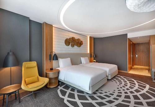 a bedroom with a white bed and a yellow chair at DoubleTree by Hilton Dubai - Business Bay in Dubai