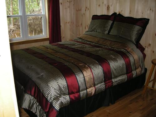 a bedroom with a bed with a comforter and a window at Chalet des Noisetiers in Tadoussac