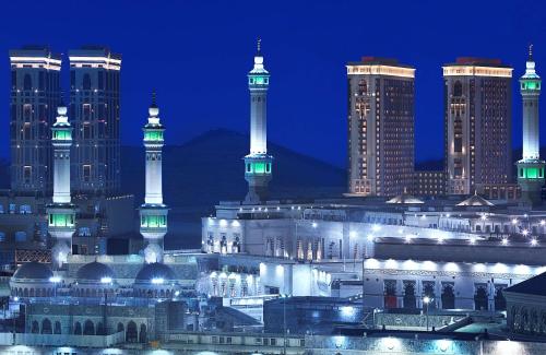 een verlichte stad 's nachts met hoge gebouwen bij Hilton Makkah Convention Hotel in Mekka