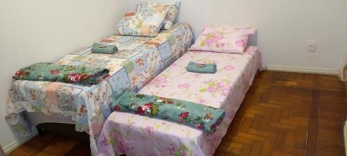 a bedroom with two twin beds with covers with bags on them at Apartamento confortável in Rio de Janeiro