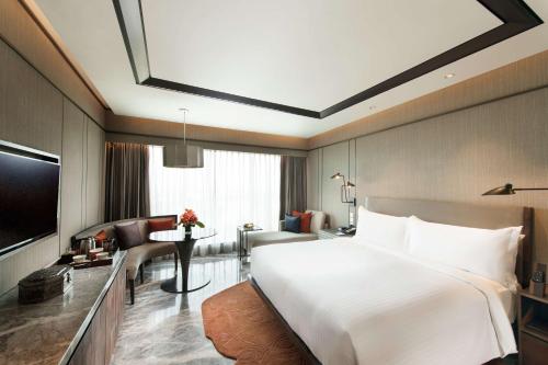 a bedroom with a large white bed and a living room at Conrad Bengaluru in Bengaluru