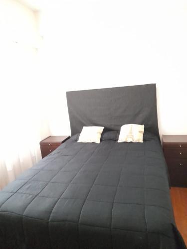 Una gran cama negra con dos almohadas. en Barracas Charme en Buenos Aires