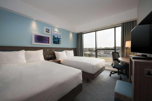 una camera d'albergo con 2 letti, una scrivania e una TV di Hampton By Hilton Edinburgh West End a Edimburgo