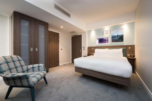 a hotel room with a bed and a chair at Hampton By Hilton Edinburgh West End in Edinburgh