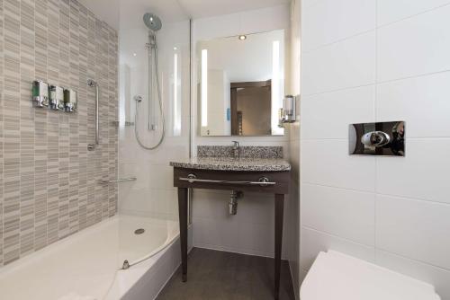 a bathroom with a sink and a shower with a mirror at Hampton By Hilton Edinburgh West End in Edinburgh