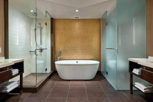 a bathroom with a tub and a glass shower at Calgary Airport Marriott In-Terminal Hotel in Calgary