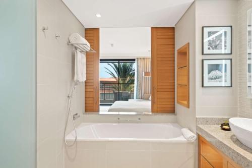 a bathroom with a tub and a sink and a mirror at Hilton Cabo Verde Sal Resort in Santa Maria