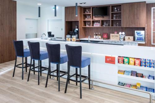 a kitchen with a bar with four blue bar stools at Hampton By Hilton Gdansk Oliwa in Gdańsk