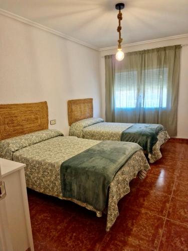 a bedroom with two beds and a window at Piso en Jarandilla de la Vera in Jarandilla de la Vera