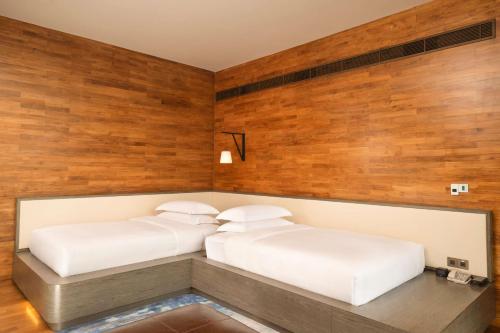 two beds in a room with wooden walls at DoubleTree by Hilton Weerawila Rajawarna Resort in Weerawila