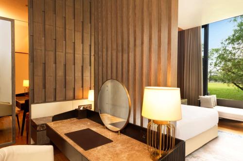 a bedroom with a bed and a mirror on a table at DoubleTree by Hilton Weerawila Rajawarna Resort in Weerawila