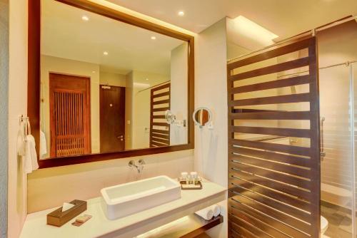 a bathroom with a sink and a mirror at DoubleTree by Hilton Weerawila Rajawarna Resort in Weerawila