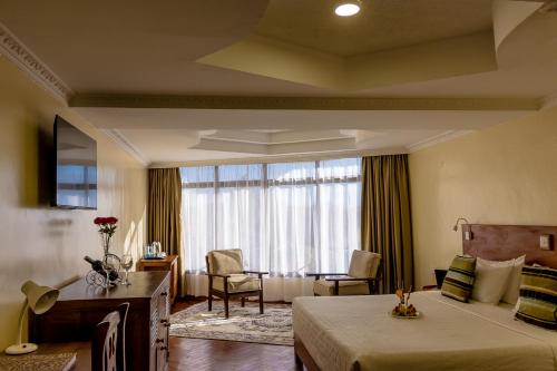 um quarto de hotel com uma cama e uma janela em The Glacier Hotel Nanyuki em Nanyuki