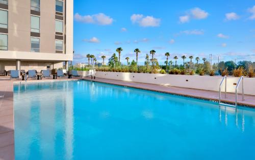 a large swimming pool in front of a building with palm trees at Hampton Inn & Suites Anaheim Resort Convention Center in Anaheim