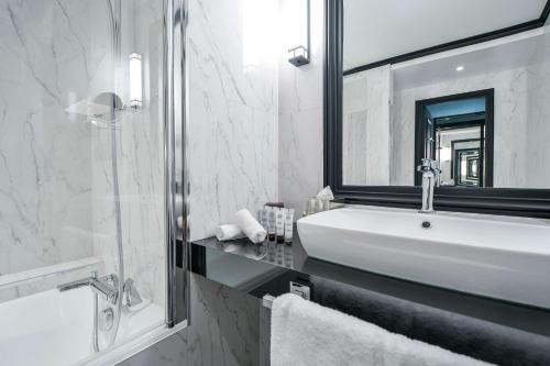 a white bathroom with a sink and a shower at Maison Astor Paris, Curio Collection by Hilton in Paris