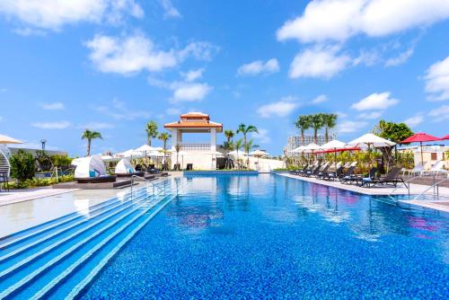 a pool at a resort with chairs and umbrellas at DoubleTree by Hilton Okinawa Chatan Resort in Chatan