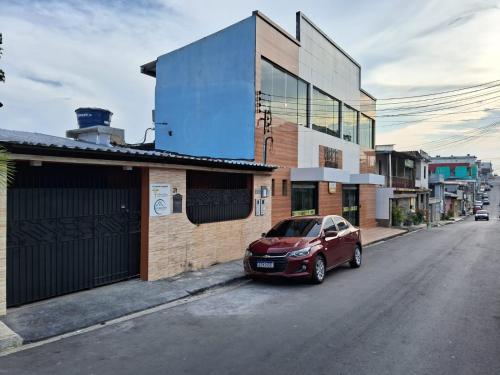 une voiture rouge garée sur le côté d'une rue dans l'établissement Alvorada Suite, à Manaus
