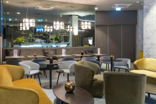 Hampton By Hilton Poznan Old Town في بوزنان: مطعم به طاولات وكراسي وثريات