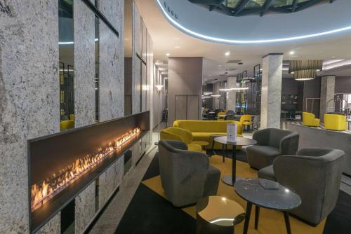 a lobby with a fireplace and yellow chairs at Hampton By Hilton Poznan Old Town in Poznań