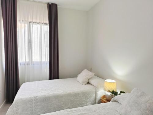 a bedroom with two beds and a window at Apartamentos MadreSelva in Fernán Pérez