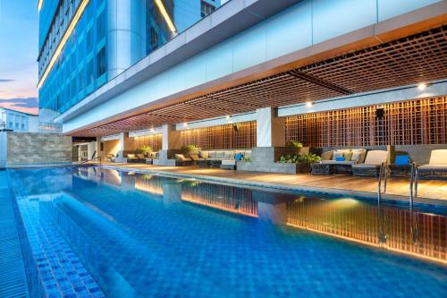 DoubleTree by Hilton Surabaya في سورابايا: مسبح وكراسي ومبنى