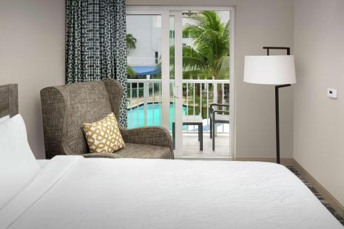 a bedroom with a bed and a chair and a balcony at Hilton Garden Inn Miami Brickell South in Miami