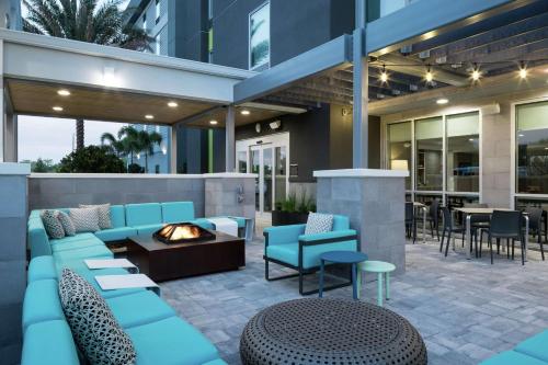 eine Terrasse mit blauen Möbeln und einer Feuerstelle in der Unterkunft Home2 Suites By Hilton Orlando Airport in Orlando