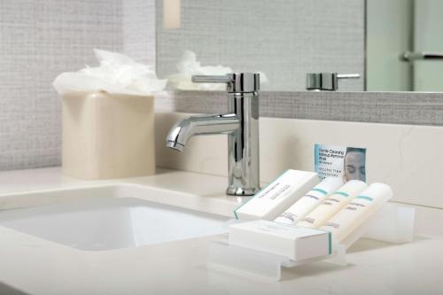 a bathroom sink with a faucet and toothbrushes at Hilton Garden Inn Miami Brickell South in Miami