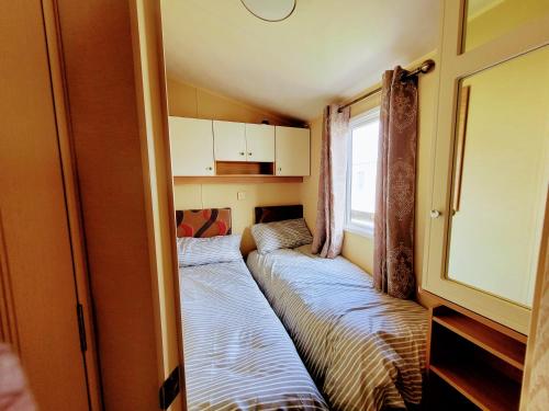 Habitación pequeña con 2 camas. en Lyons Robin Hood Holiday Park, The Shamrock Way, en Meliden
