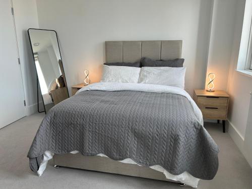 um quarto com uma cama com um edredão cinzento e um espelho em Luxurious two-bedroom flat with scenic views em Londres