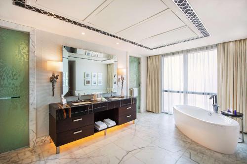 baño con bañera grande y espejo grande en Hilton Dubai Al Habtoor City, en Dubái