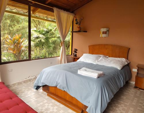 a bedroom with a bed and a large window at Senz Chalet Riverside - Mindo in Mindo