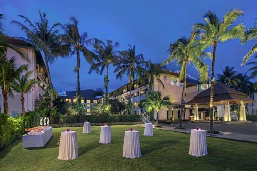 een rij tafels voor een hotel met palmbomen bij DoubleTree by Hilton Phuket Banthai Resort in Patong Beach